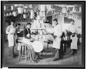 Giovani nativi americani in officina di lavorazione dei metalli con secchi, vasche da bagno, annaffiatoi e altri oggetti metallici, Carlisle Indian School, Pennsylvania, c.1904 (foto in b/n)